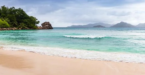 Panoramic La Digue beach view with mountains of Praslin island Stock Photos