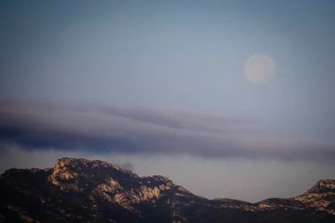 Panoramic of the moon setting behind the mountains Stock Photos