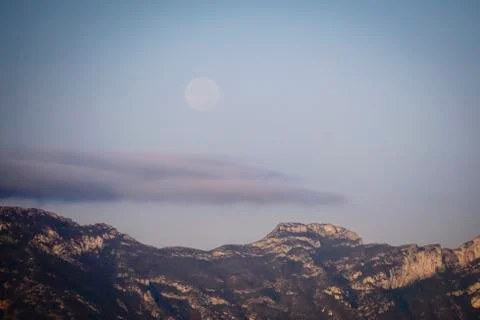 Panoramic of the moon setting behind the mountains Stock Photos
