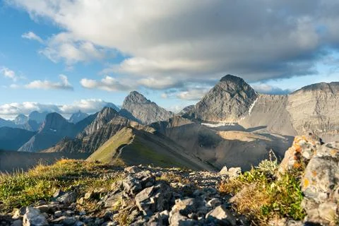 Panoramic mountain range view under blue sky with fluffy clouds and sunshine. Stock Photos