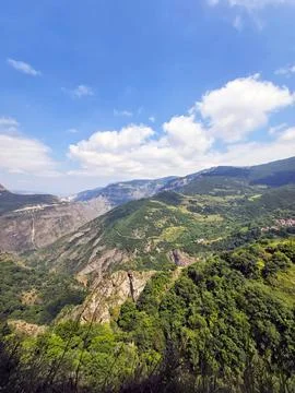 Panoramic mountain view with lush forests under clear blue sky Stock Photos