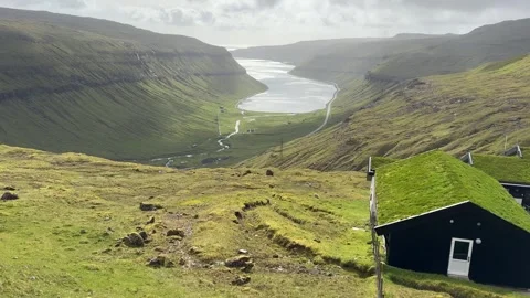 Panoramic mountain view with a traditional grass-roofed house in the foreground  Stock Footage 334870125