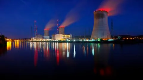 Panoramic night shot of a large nuclear power plant close to a river with blu Stock Photos