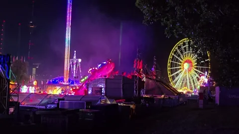 Panoramic Night View of a Fairground with Ferris Wheel and Thrill Rides Stock Footage 341628749