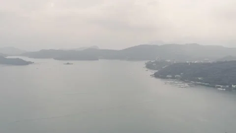 Panoramic pan move. Aerial drone shot of overcast Sun Moon Lake with hazy hil 스톡 동영상 186963071
