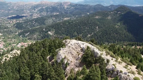 Panoramic rugged mountain with forest slopes above traditional village rooftops Stock Footage 344095281