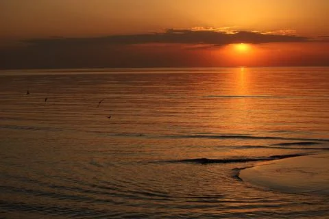 Panoramic seascape during a dramatic golden sunset. Dark clouds hover over the Stock Photos