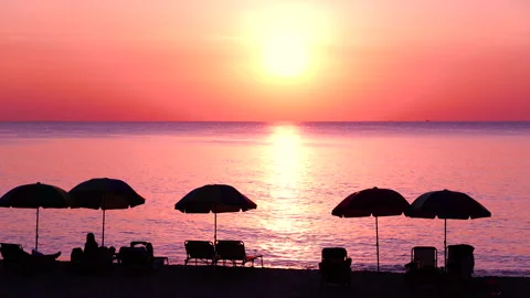 Panoramic seascape sunset beach umbrellas sand colorful dramatic twilight sky. Stock Footage 208630308