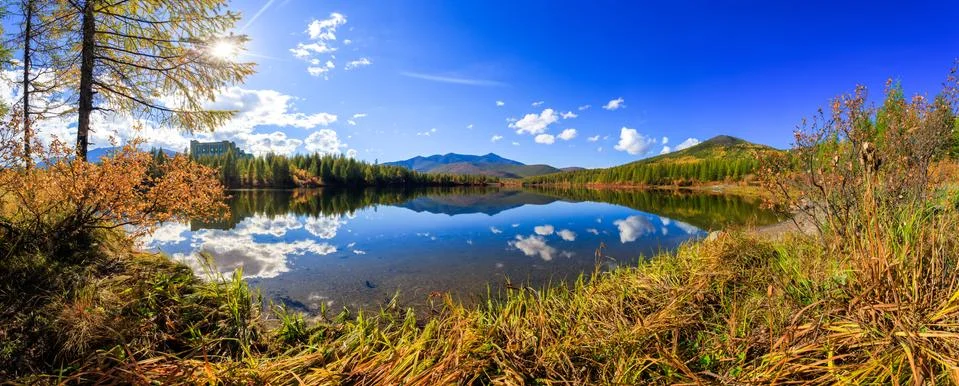 Panoramic shot. A beautiful flat surface of the lake against the background o Stock Photos