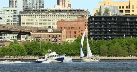 Panoramic shot of Brooklyn skyline with sail boat and NYPD boat passing by Video stock 77279915