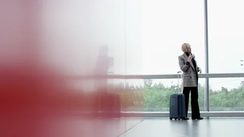 A panoramic shot of a middle aged blonde business woman standing in the airport Vídeos de archivo 135868629