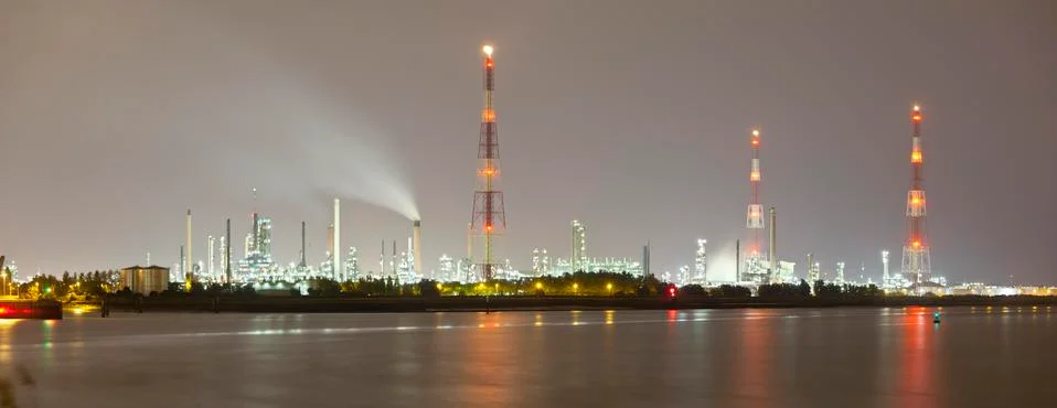 Panoramic shot of multiple oil refineries with tall gas flare stacks in the h Stock Photos