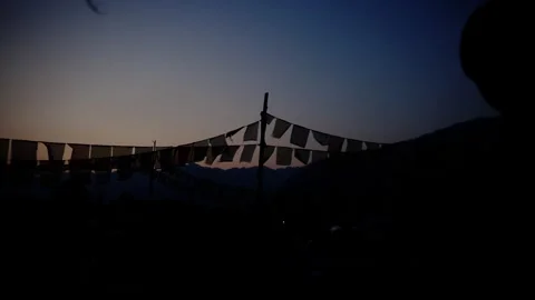 Panoramic silhouette of prayer flags stretching across a colorful dusk sky Vídeos de archivo 343142397