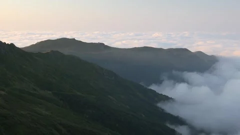 Panoramic slanting sun rays above cloud sea and mountain slopes in northern Stockbeeldmateriaal 333782513