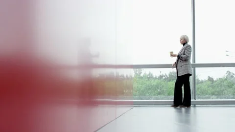 A panoramic slow motion shot of a young blonde business woman standing in an Stock Footage 135870207