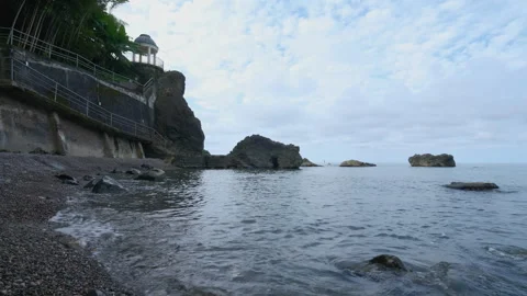 Panoramic Stony Beach View Facing Cliffside Gazebo Video stock 347996404