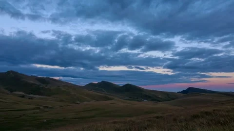 Panoramic time lapse of clouds above mountains and green hills at sunset Stock Footage 247740387
