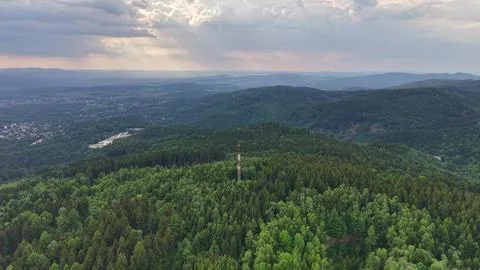 Panoramic valley view over forested hills with tall communication tower, su.. Stock Photos