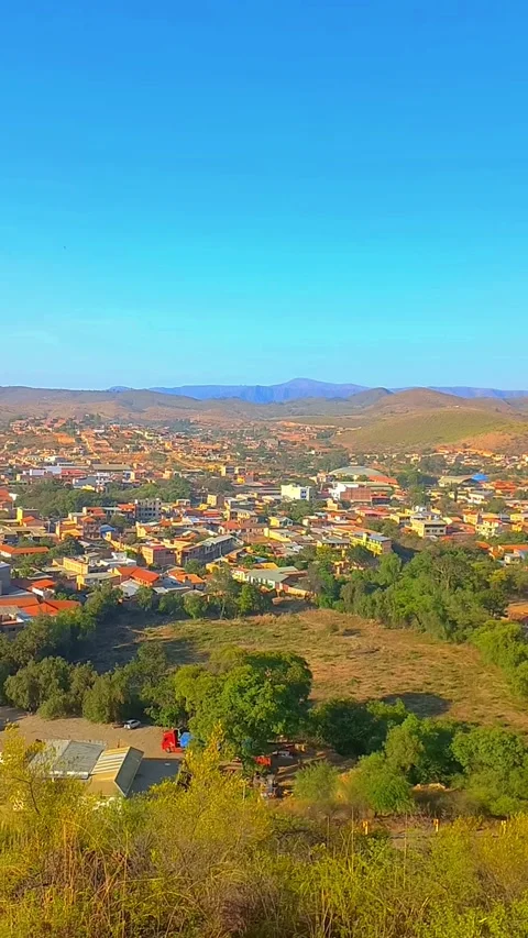 Panoramic vertical view of a small town nestled in a valley surrounded by green  動画素材 323241089