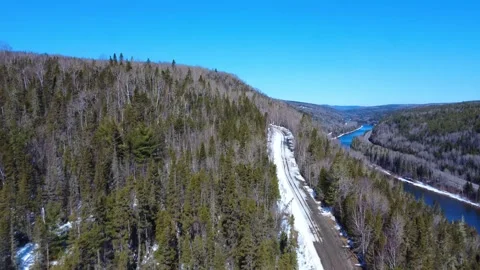 Panoramic view from above a forest road leading into snow-capped mountains. Stock Footage 306881336