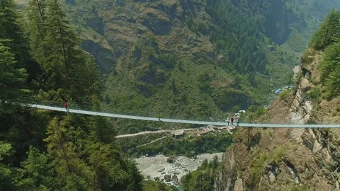 Panoramic view above narrow suspension bridge over green forest river gorge Stock Footage 124680907