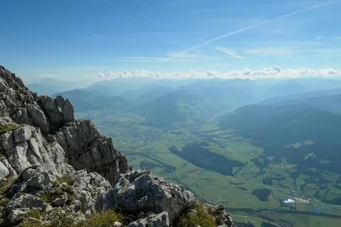 A panoramic view from an Alpine top on a vast valley with sharp mountains Stock Photos