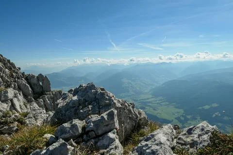 A panoramic view from an Alpine top on a vast valley with sharp mountains Stock Photos