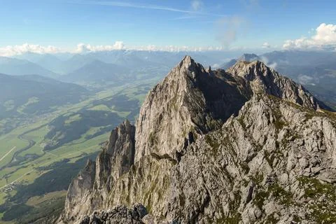 A panoramic view from an Alpine top on a vast valley with sharp mountains Stock Photos