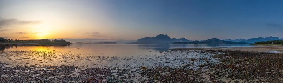 Panoramic view from beach of the setting sun on Amnesvika bay with mountains  Stock Photos