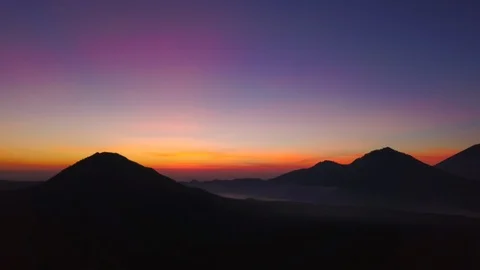 Panoramic view of bright colorful sunset silhouette volcano Batur drone footage Stock Footage 89554004