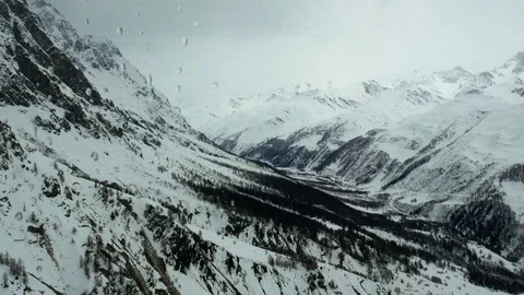 Panoramic view from cabin on cable car while driving over mountain peaks snow Video stock 82890959