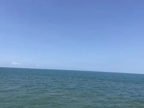 Panoramic view of the calm blue sea meeting the clear sky on a sunny day Vidéo 334163488
