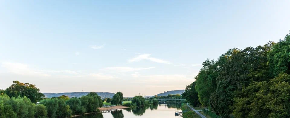 Panoramic view of a calm river winding between wooded banks and open meadows Stock Photos