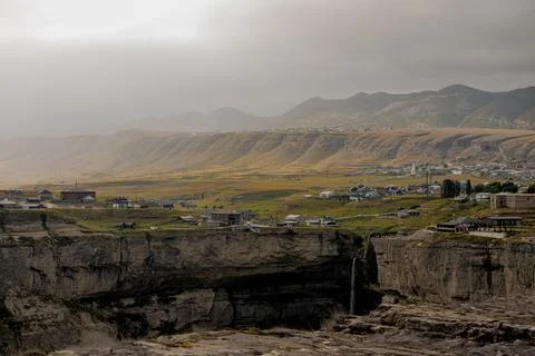 Panoramic view of the Caucasus mountains with rolling hills and a small village Stock Photos