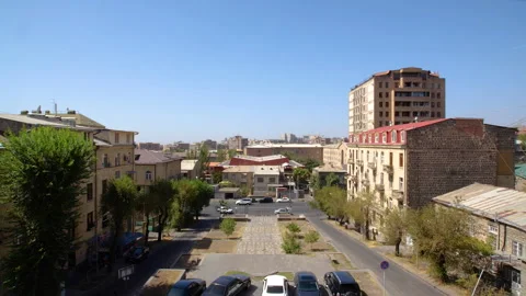 A panoramic view of the cityscape with blue sky, trees, cars, people, and Stock Footage 278057742