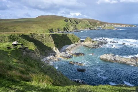 A panoramic view of the Cleggans Cliffs in Ireland with a rough Atlantic ocean Stock Photos
