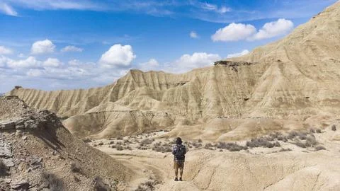 Panoramic view of the colored stone desert and traveler on his back walking.. Stock Photos