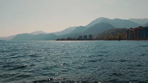 Panoramic view of dark alpine lake with mountains and lakeside town in northern Stock Footage 332809881