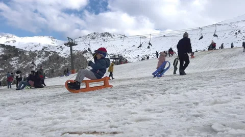 Panoramic view of Davraz ski resort, children on sleighs and skiers sliding down Stock Footage 231842300