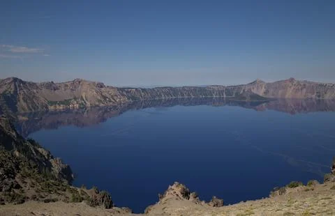 A panoramic view of deep blue Crater Lake in Oregon, reflecting clear sky a.. Stock-Fotos