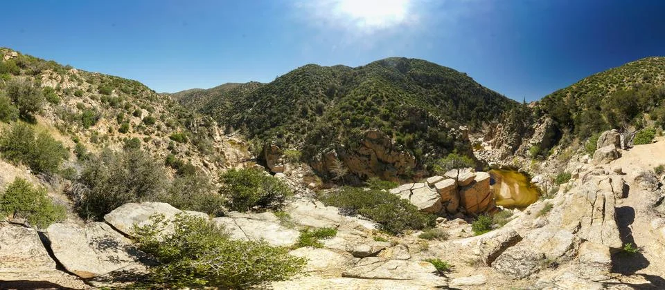 A panoramic view of a desert with a small stream running through it Stock Photos