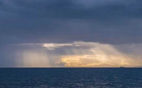 Panoramic view of dramatic clouds and a container ship on the horizon. Sunlight  Stock Photos