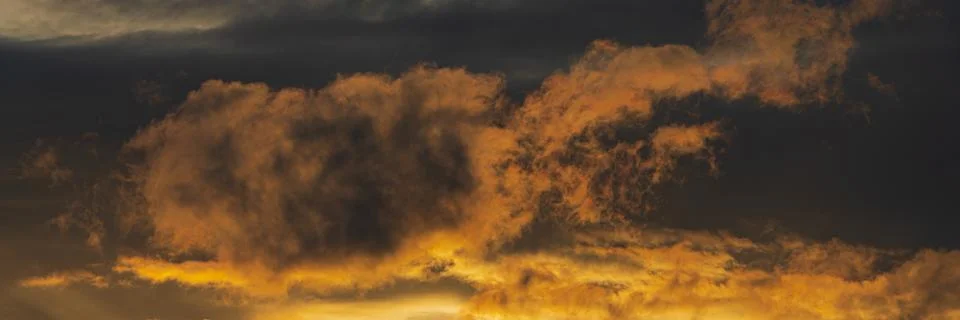 Panoramic view of dramatic clouds illuminated rising of sun in sky to change Foto stock