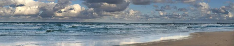Panoramic view of a dramatic ocean scene with crashing waves under a cloud... Stock Photos