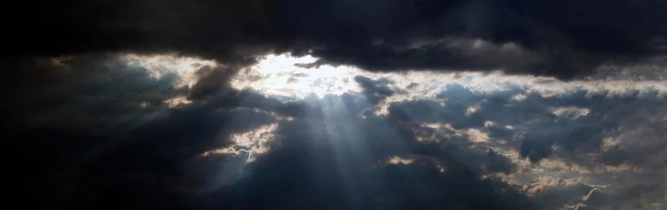 A panoramic view of a dramatic sky with rays of sunlight breaking through h.. Stock Photos