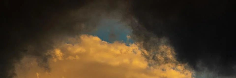 Panoramic view of dramatic storm clouds illuminated rising of sun floating in Stock-Fotos