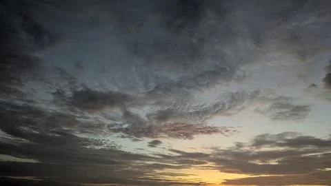 A panoramic view of a dramatic sunrise sky with dark, textured clouds stret.. Photos