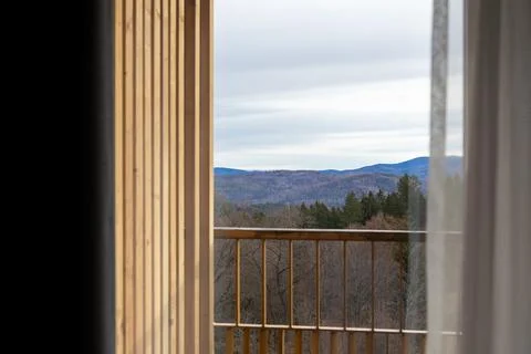 A panoramic view of forested mountain ridges framed by a wooden balcony railing Stock Photos