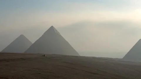 Panoramic view of the Giza Pyramids silhouettes in the distance at sunrise Vídeos de archivo 341838284