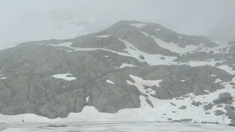 Panoramic view of a glacier mountain with clouds and a small frozen lake Stock Footage 194840136